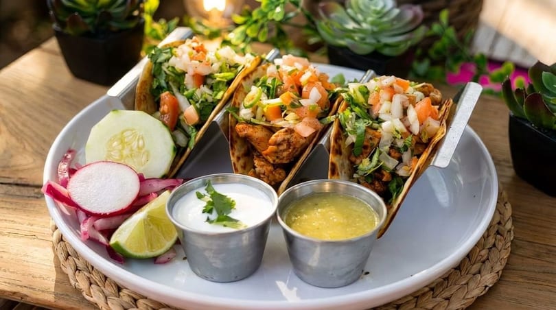 Three chicken tacos with pico de gallo, lime, cucumber, radishes, sour cream, and salsa verde.